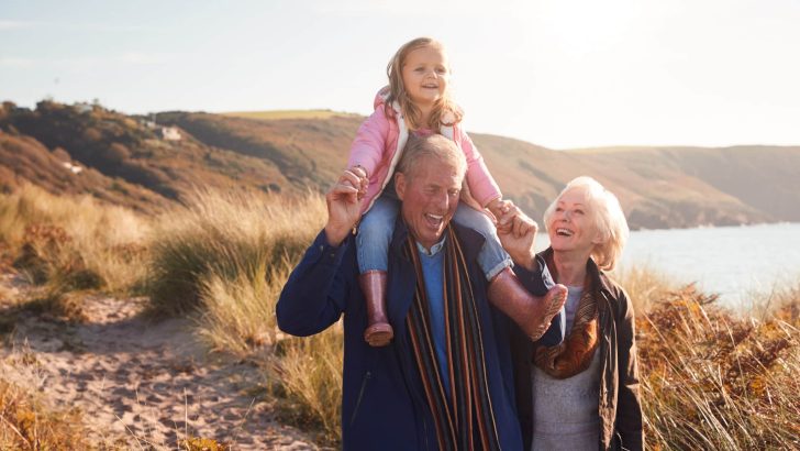 Grandfather,Giving,Granddaughter,Ride,On,Shoulders,As,They,Walk,Through